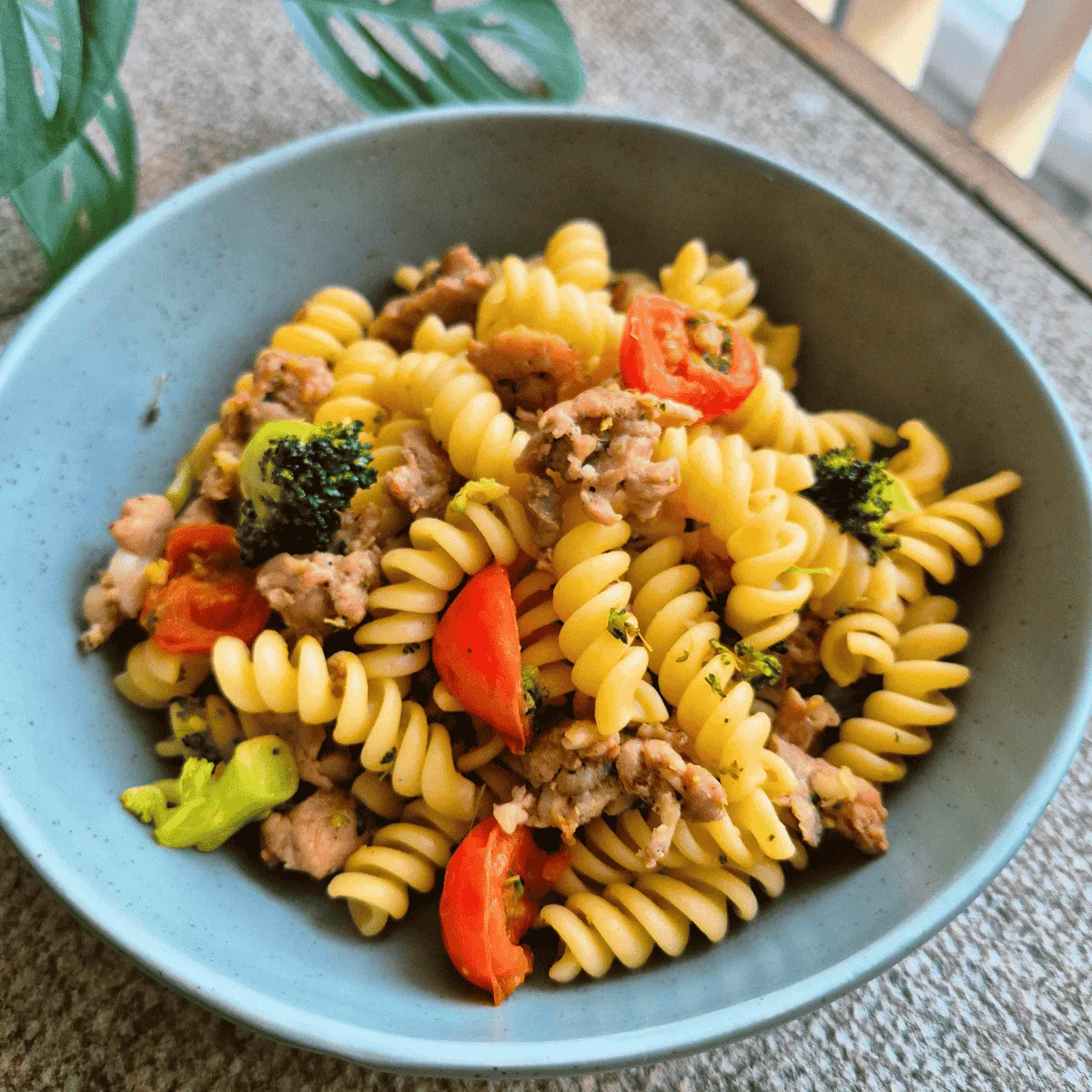 Tomato, Broccoli & Pork Pasta in green bowl
