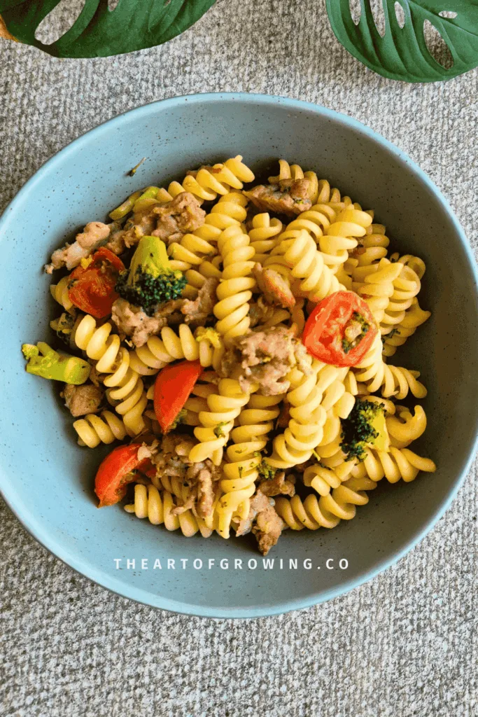 Pasta, cherry tomato, broccoli and pork meat in green bowl on grey tabletop