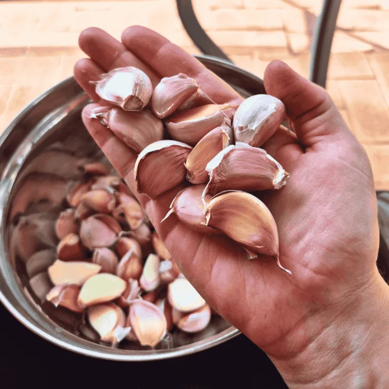 hand holding garlic cloves with bowl in background