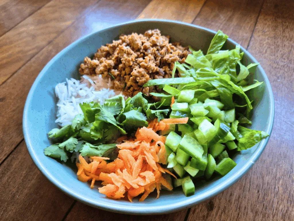 asian salad with mince meat in green bowl on jarrah floorboards
