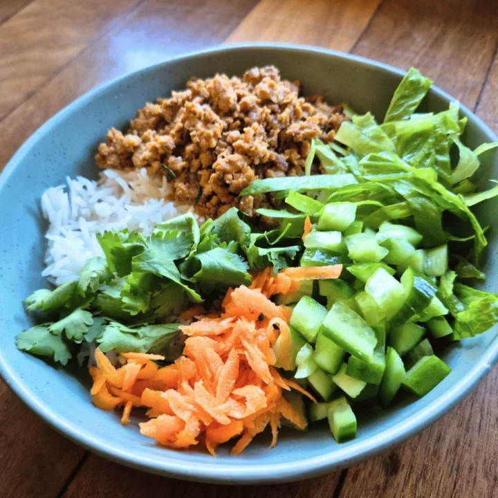 asian salad with mince meat in green bowl on jarrah floorboards